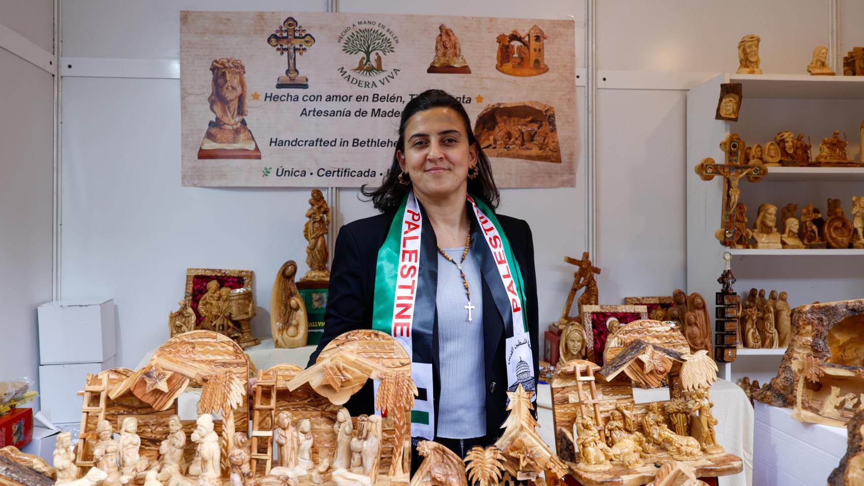 Gloria posa en su puesto en la feria de artesanía, en Toledo, con una bandera de Palestina colgada del cuello.