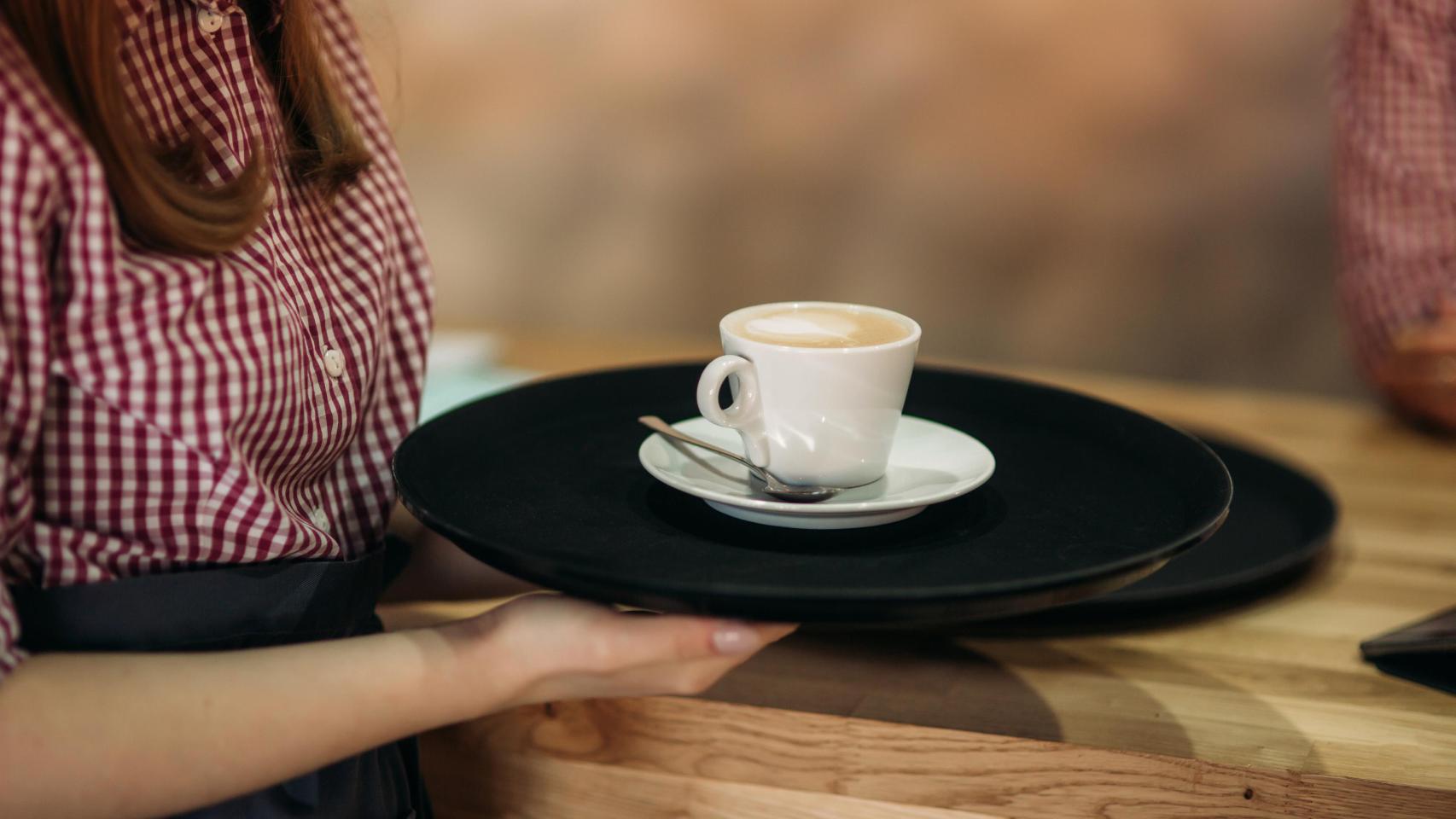 Una camarera sirviendo un café.