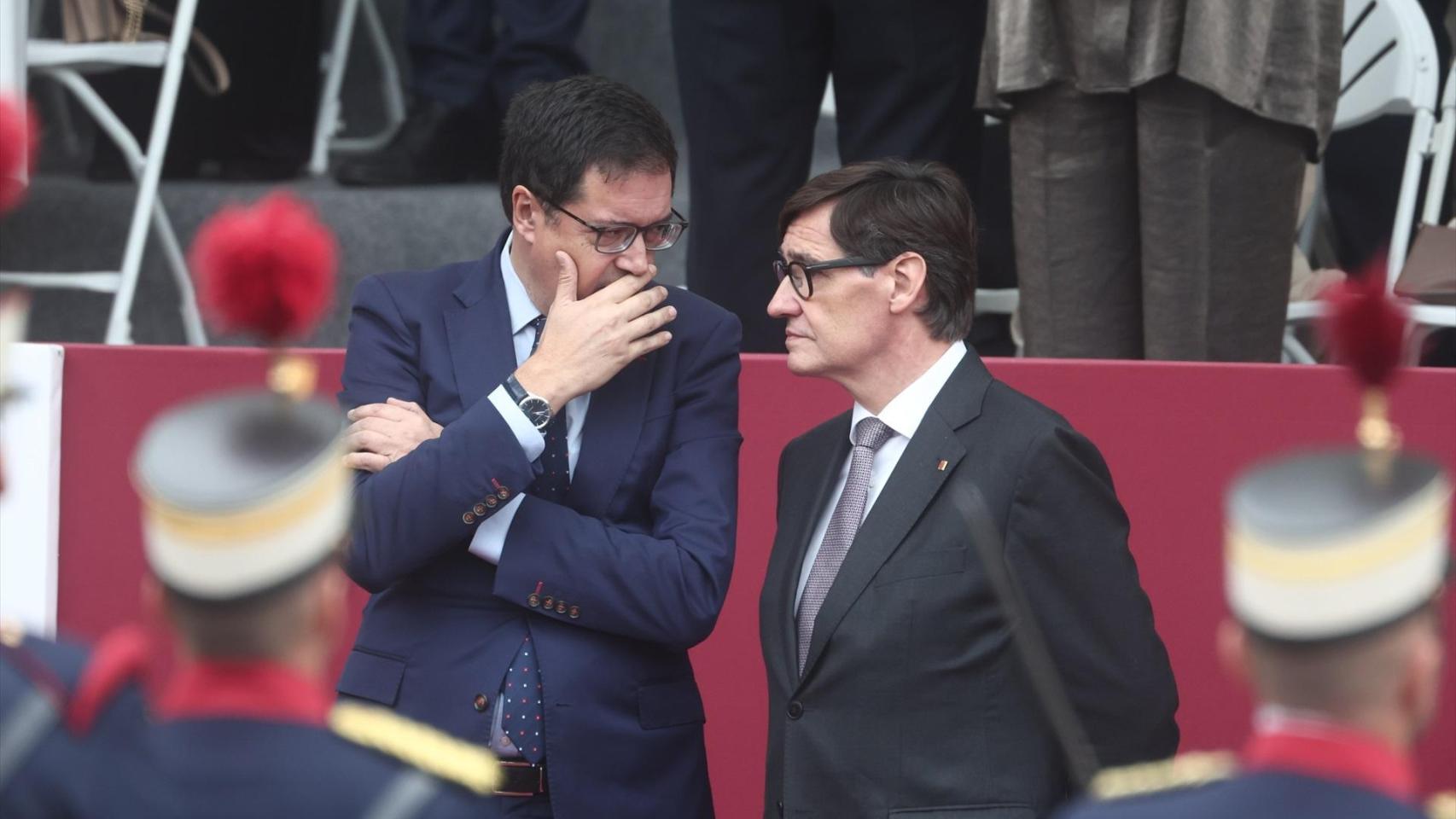 Salvador Illa conversa con el ministro Óscar López, este domingo, durante el desfile del 12 de octubre en Madrid.