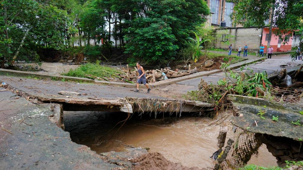 Un hombre camina sobre un puente dañado por las lluvias torrenciales en Jalcocotán, México.