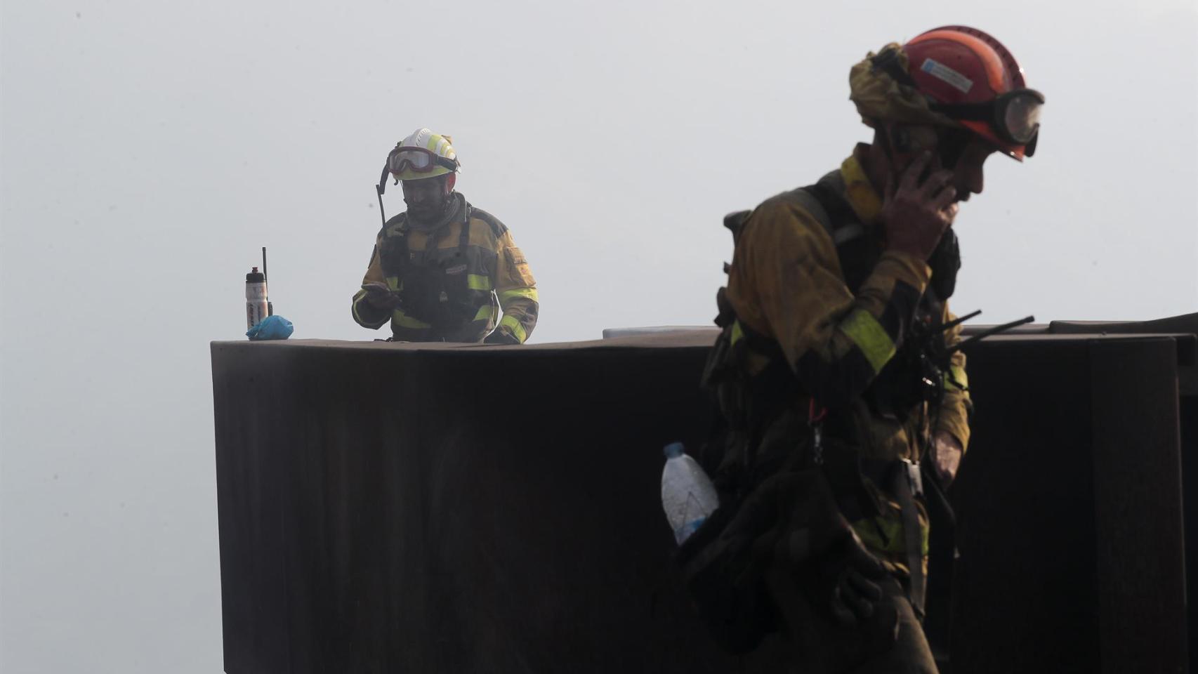 Dos brigadistas forestales observan el terreno calcinado, a 20 de septiembre de 2025, en A Barca, Sober, Lugo