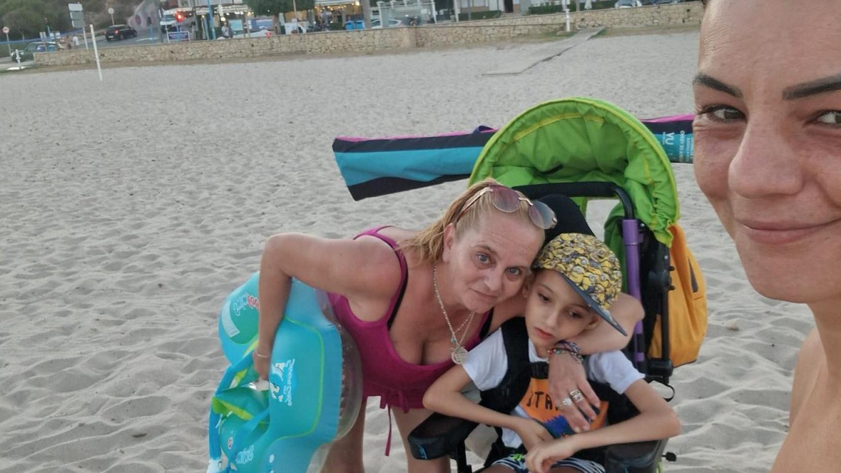 Ian, junto a su madre y su abuela, en la playa de Muchavista, donde la pasarela de madera no llega hasta la orilla.