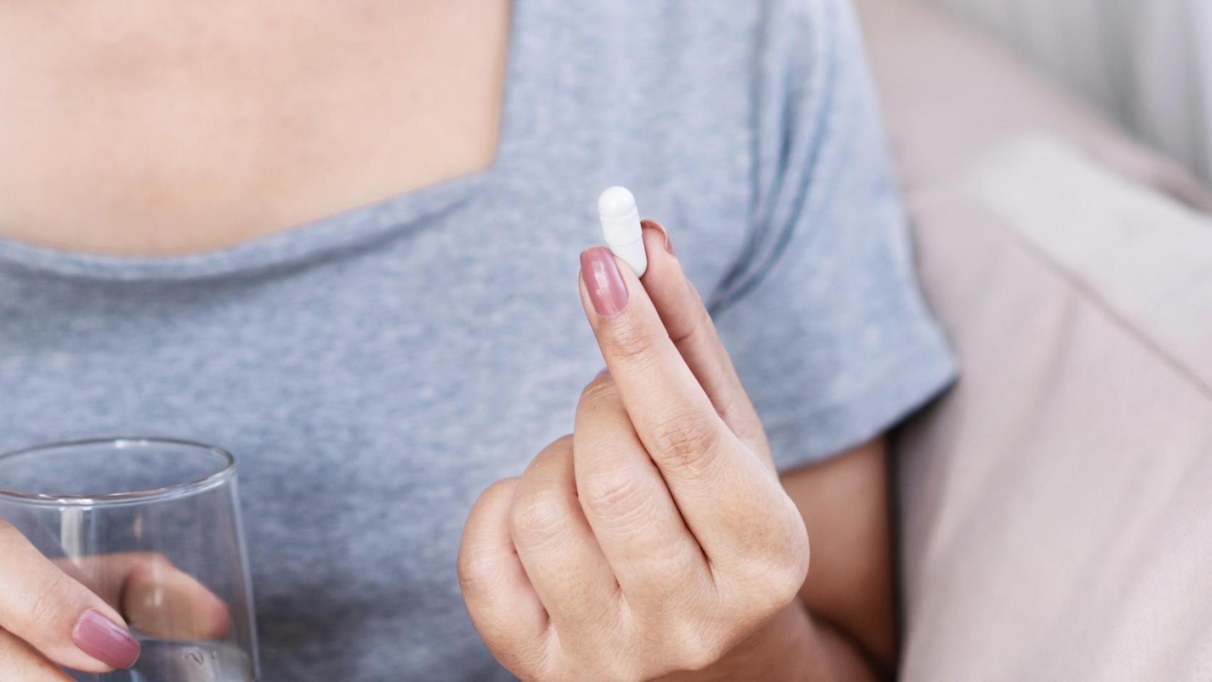 Primer plano de la mano de una mujer con una pastilla