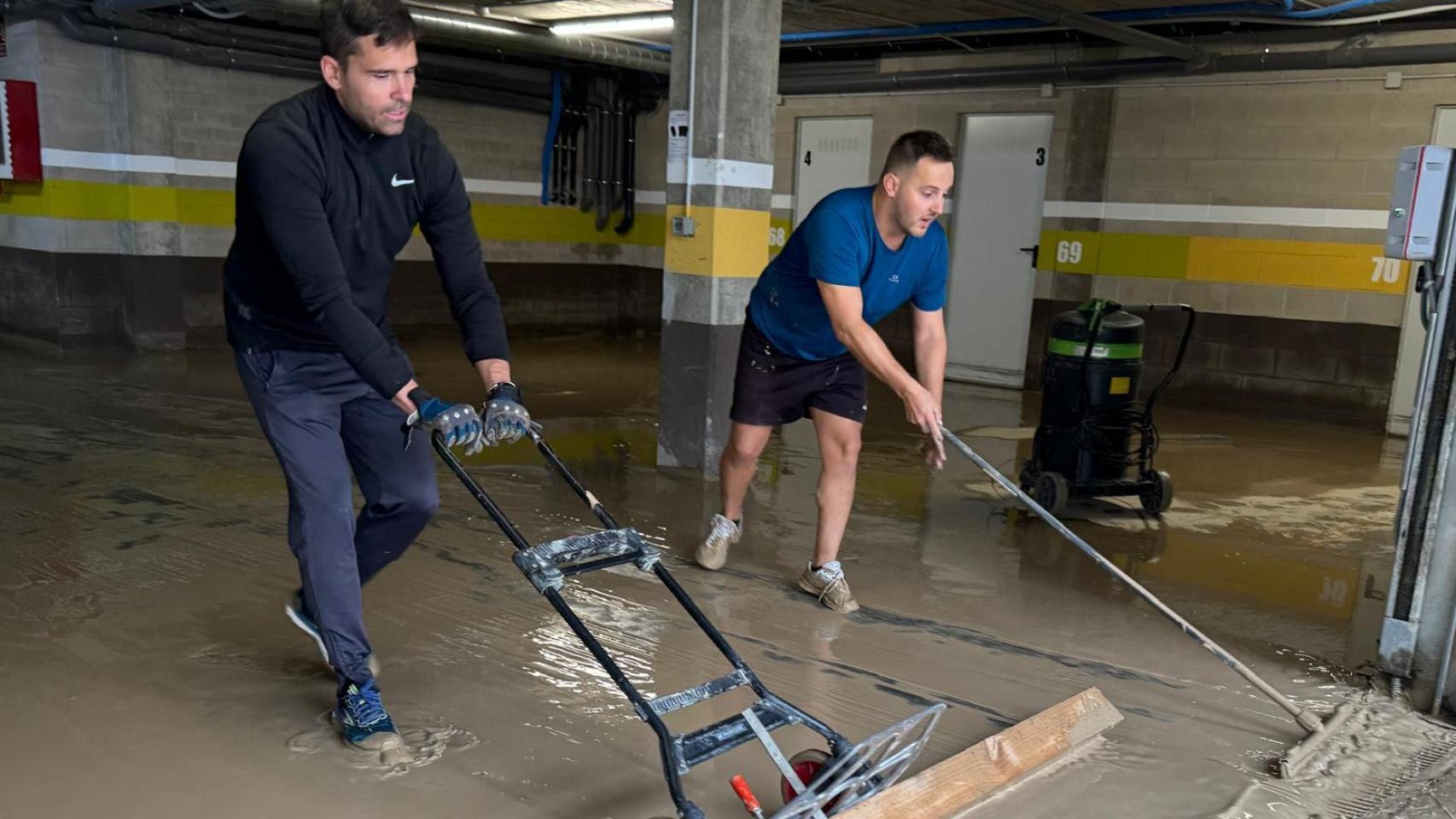 Vecinos de Cuarte achican el agua de un garaje tras las inundaciones de septiembre.