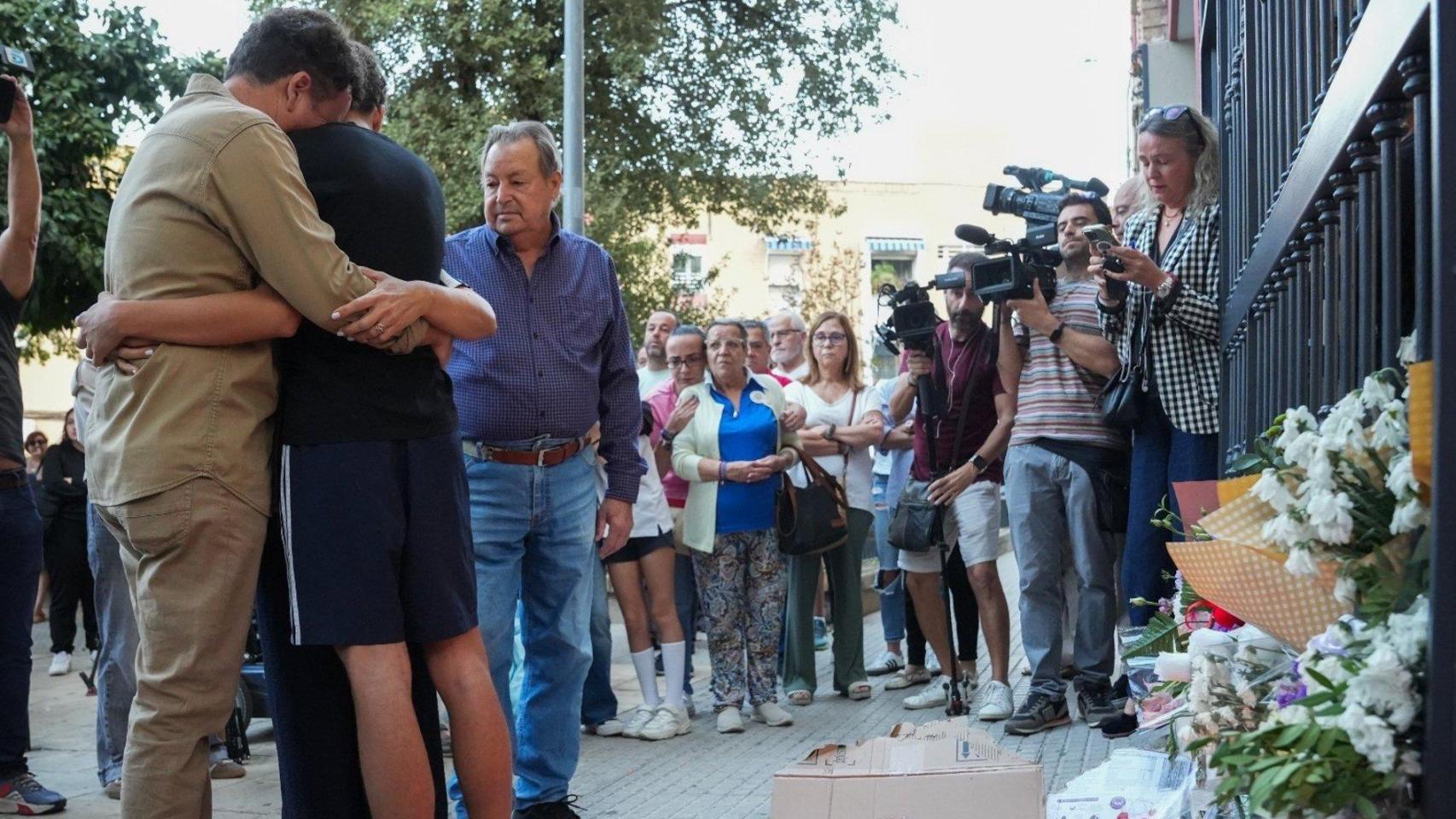 La familia de Sandra Peña se abraza en el portal de su casa delante del altar improvisado por su muerte.