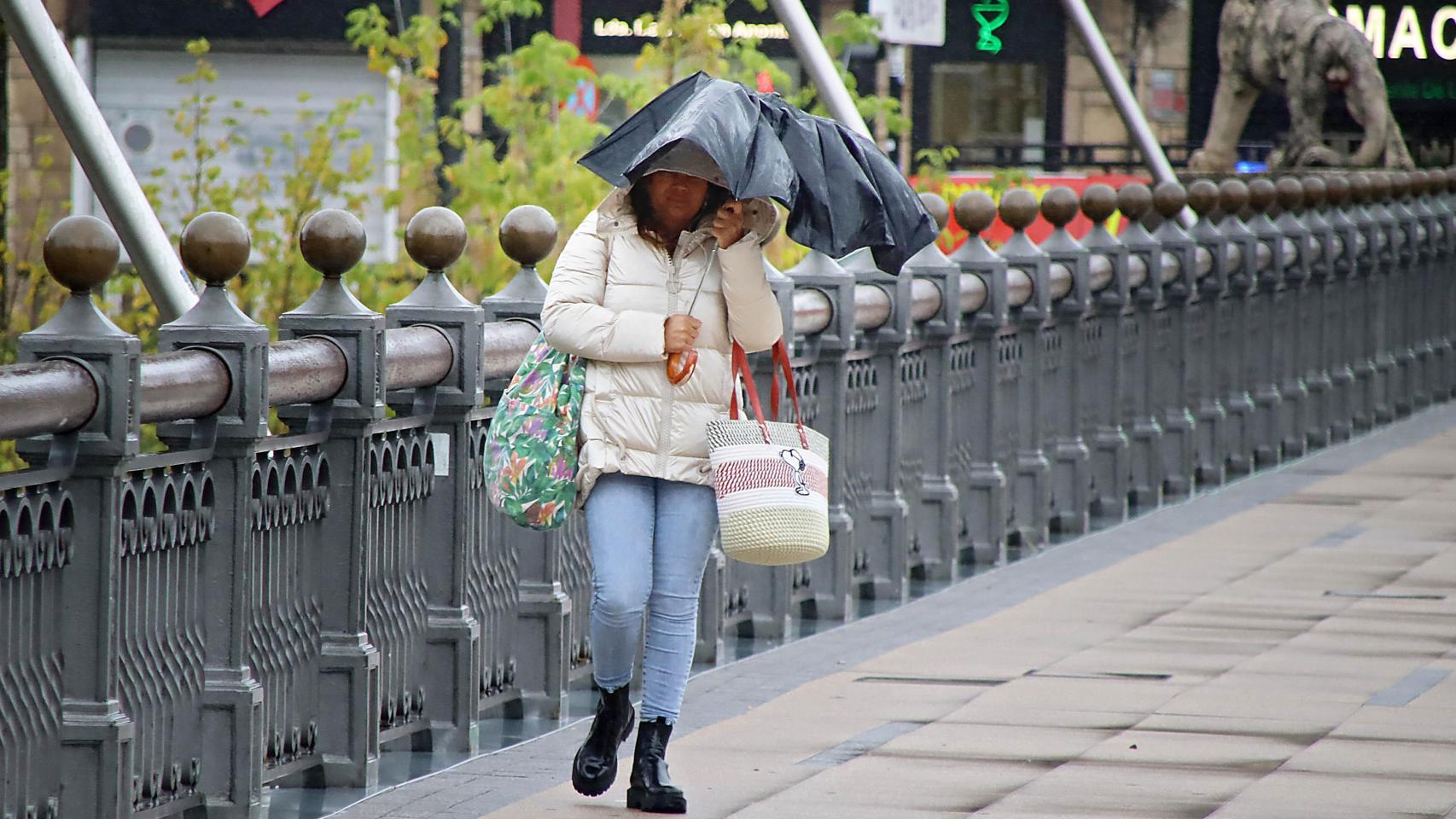 Una mujer se protege de la lluvia en León