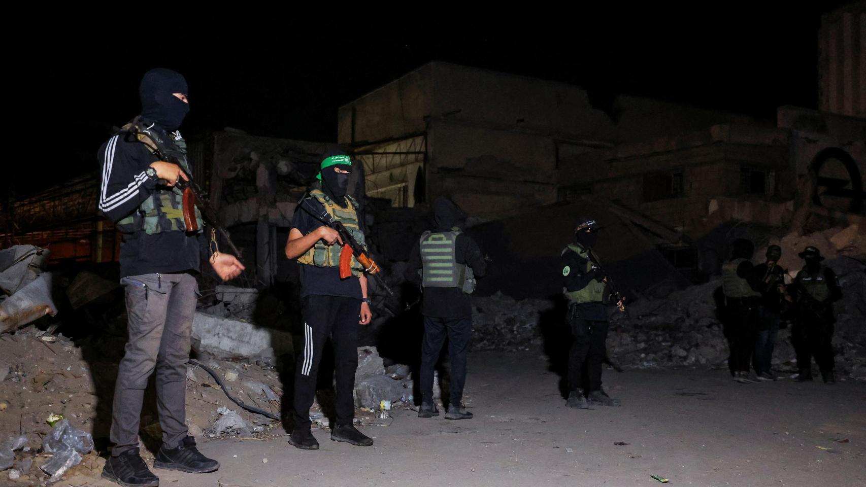 Militantes de Hamás hacen guardia mientras vehículos de la Cruz Roja recogen el pasado 15 de octubre los cadáveres de rehenes israelíes.