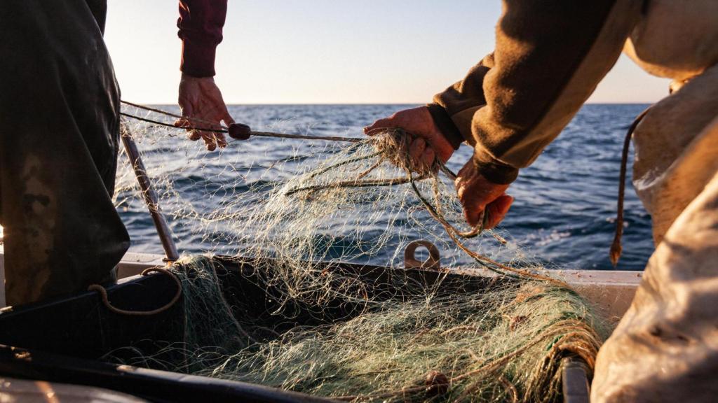 Pescador trabajando tirando de la red de pesca en un barco de arrastre.