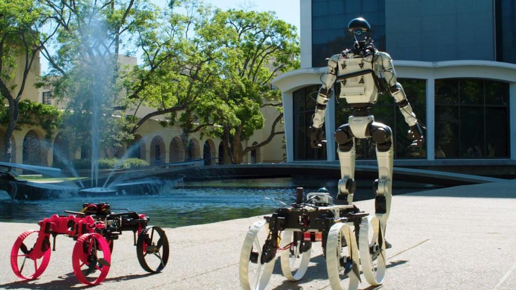 El robot humanoide con dos drones en el suelo.