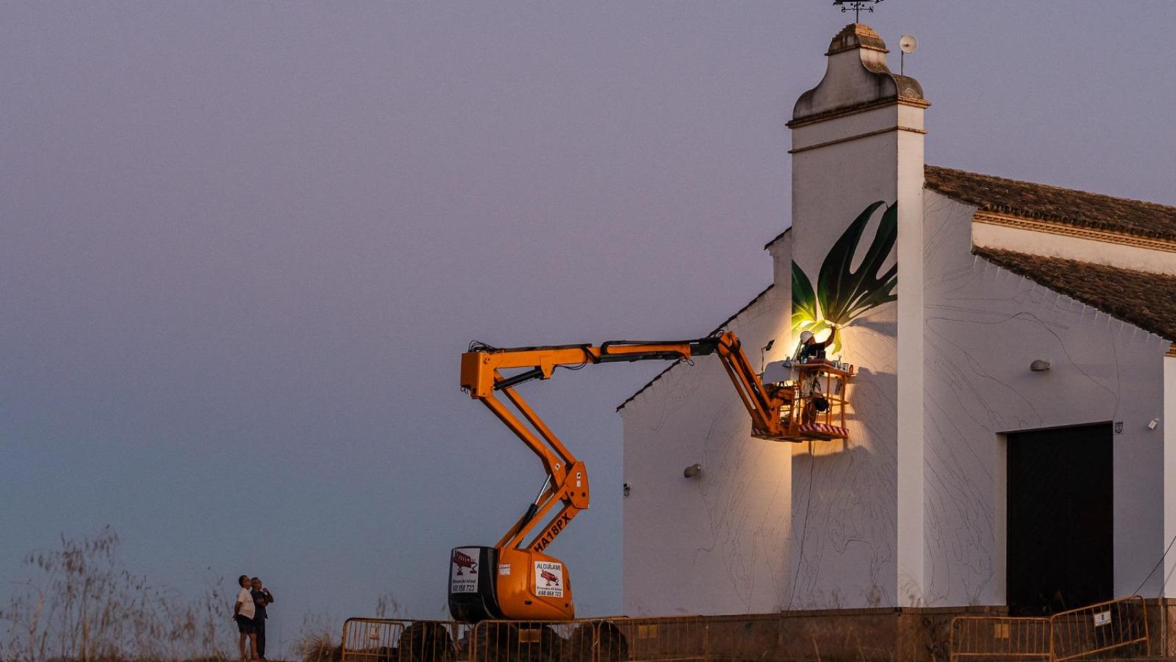 El artista Manuel León en la tarea de pintar el mural a la entrada de Villanueva del Ariscal.