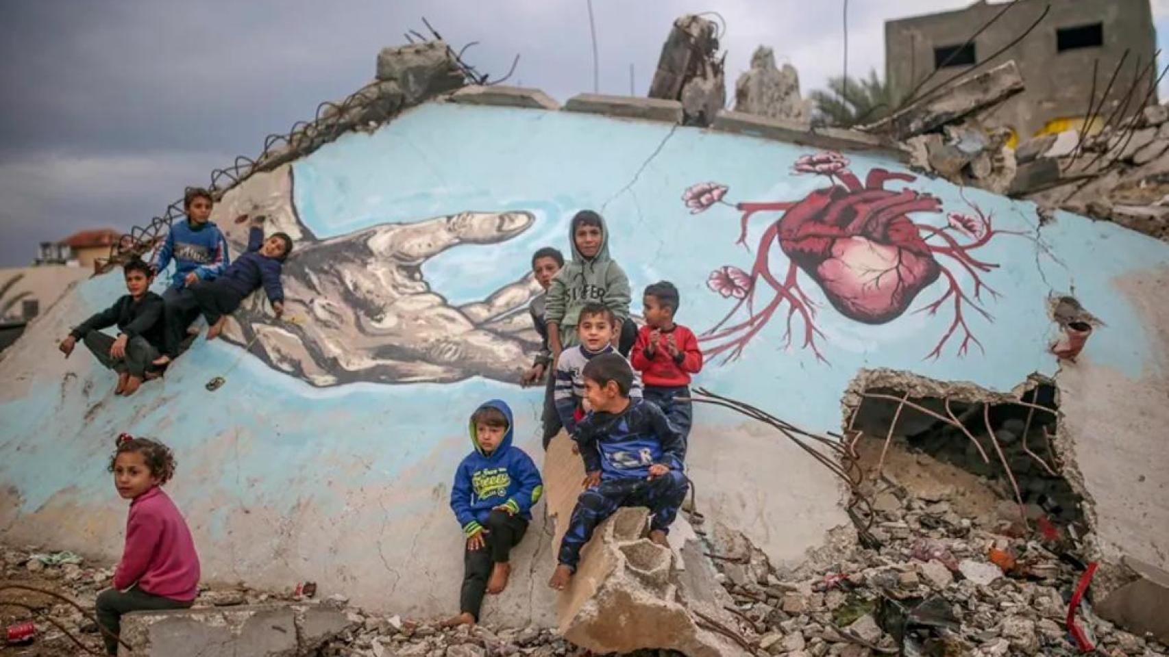 Imagen de archivo de niños palestinos desplazados internamente jugando junto a un mural en Deir Al Balah (Gaza).