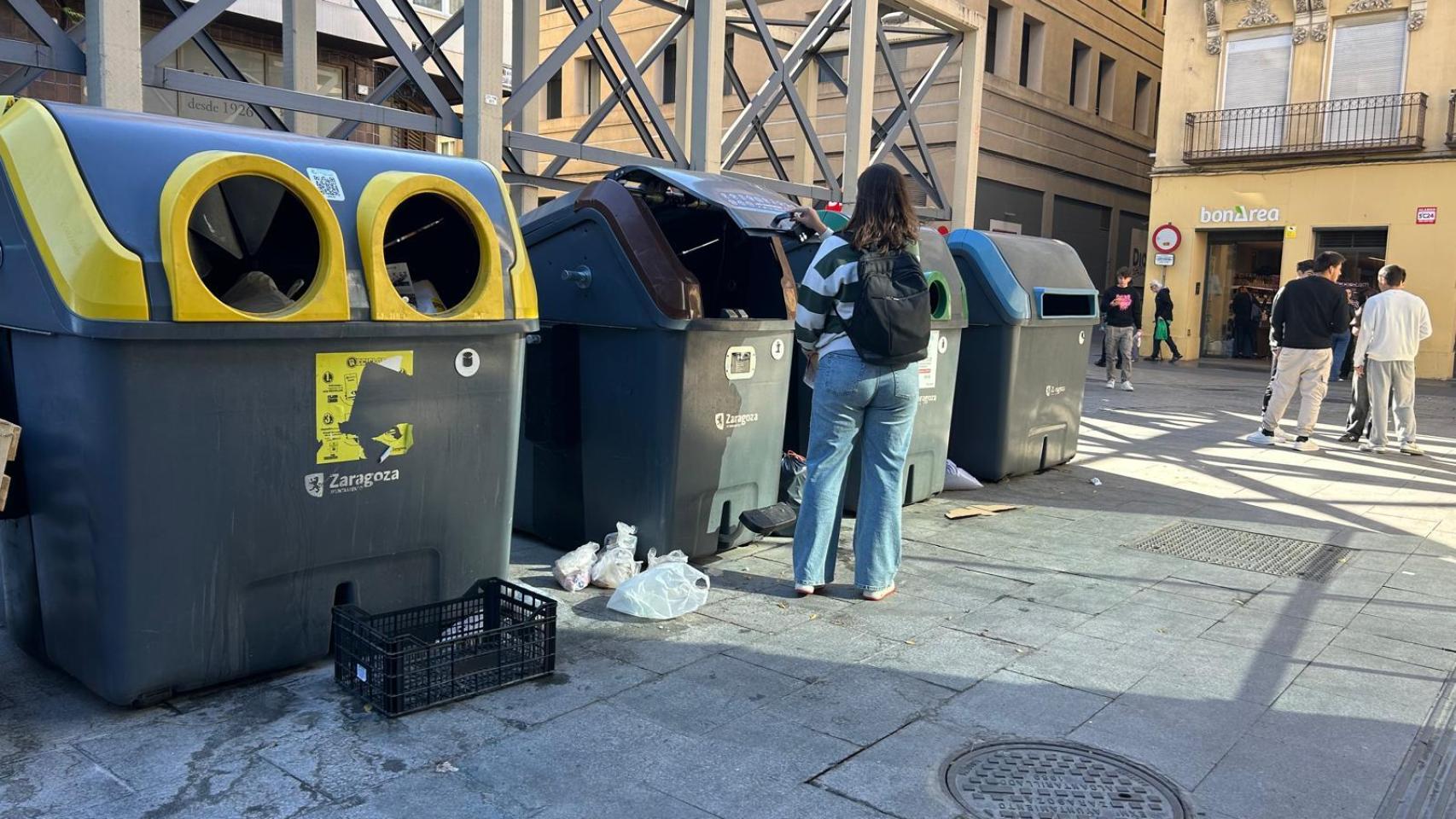 Una joven tirando basura en un contenedor en Zaragoza.