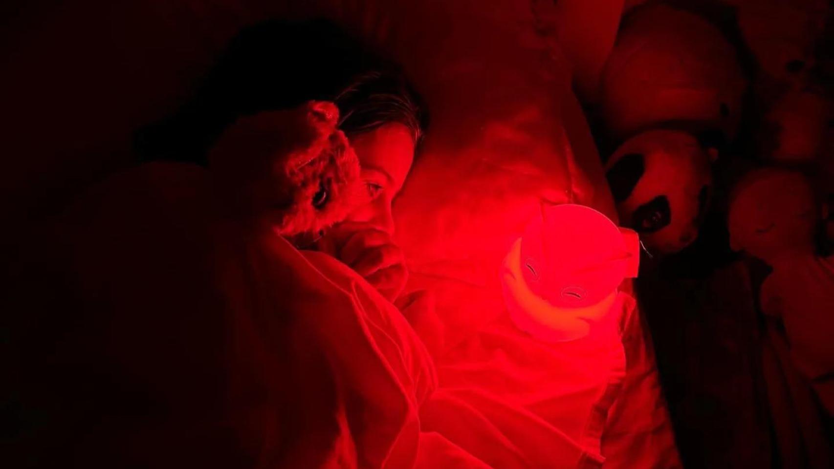 Una persona duerme frente a una luz roja.